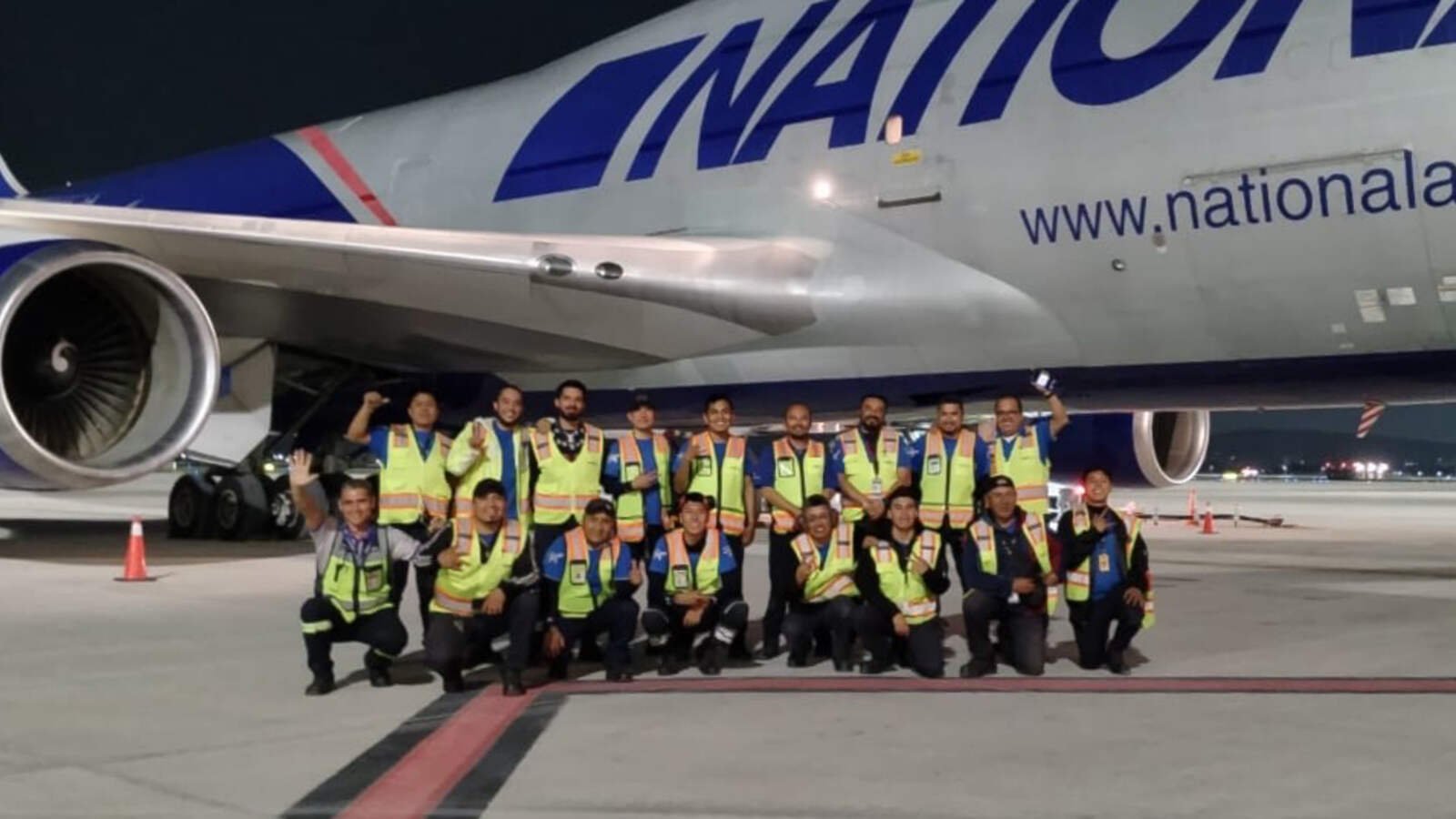 SATISERCOM ground handling team in high-visibility equipment in front of a National Airlines freighter