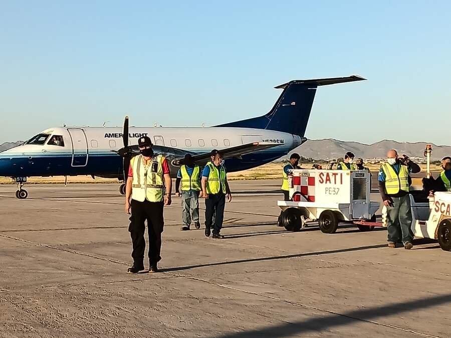 SATISERCOM ramp crew walking toward an aircraft with ground support equipment